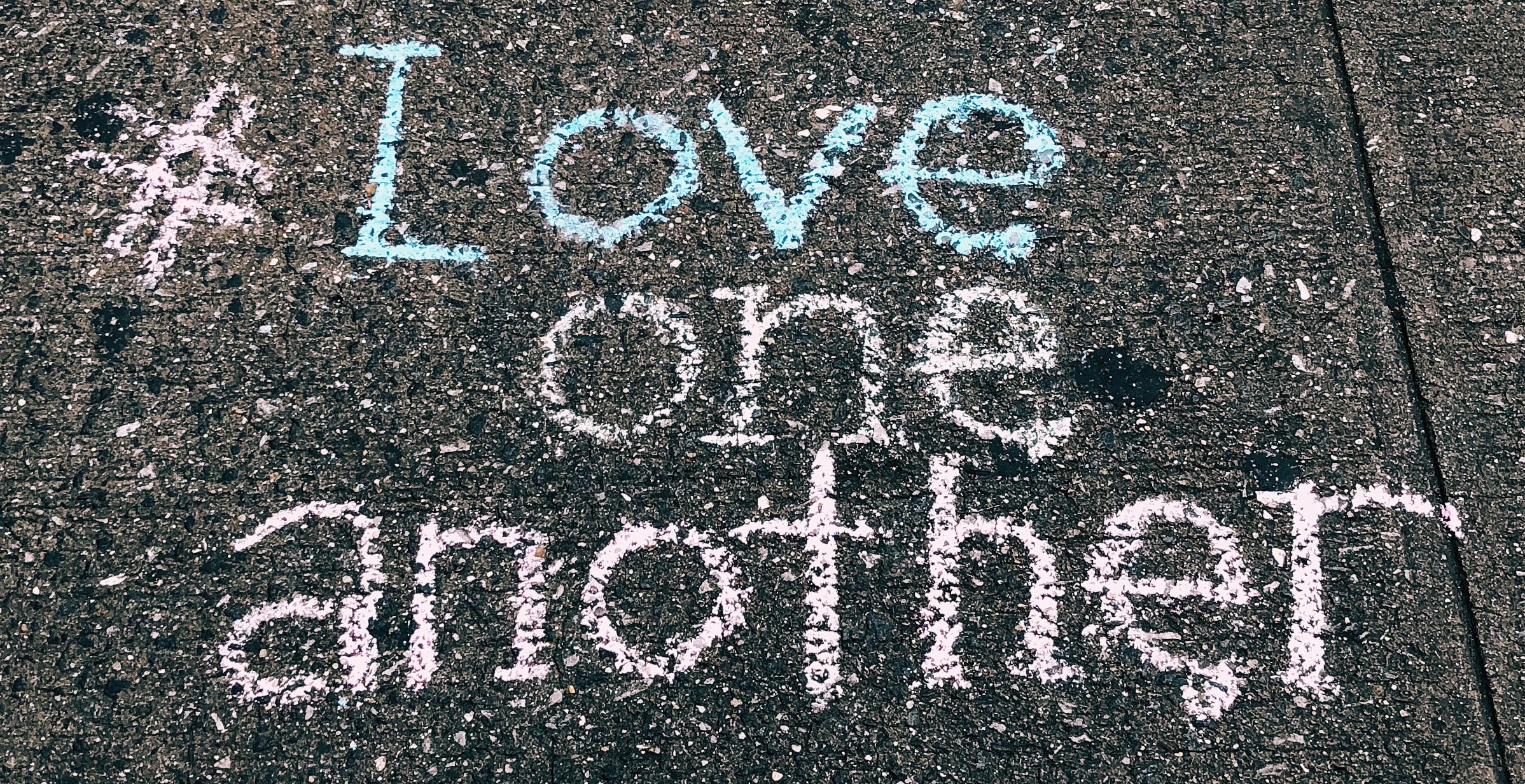 #Love one another written in chalk on a sidewalk